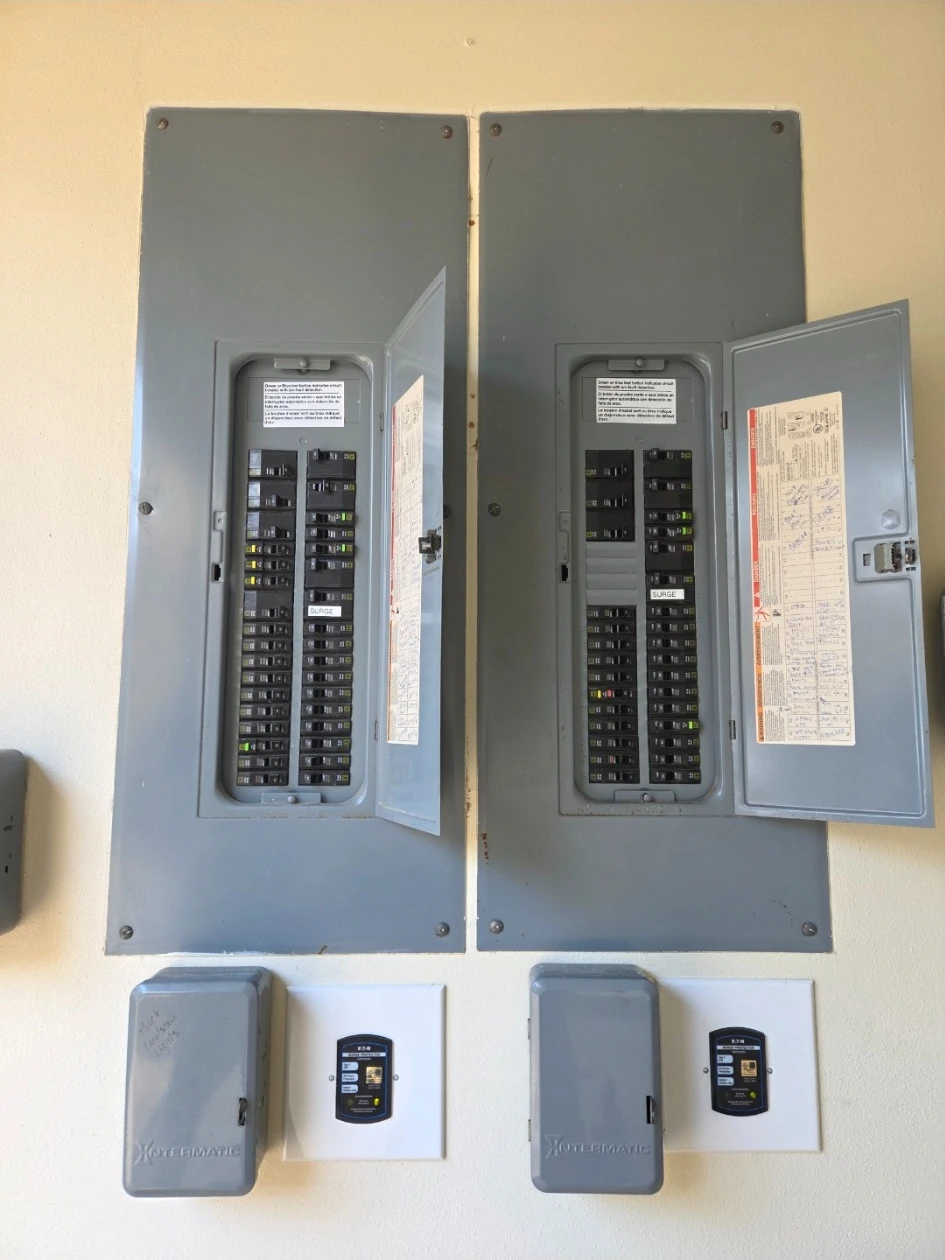 Two whole home surge protectors installed below two panels
